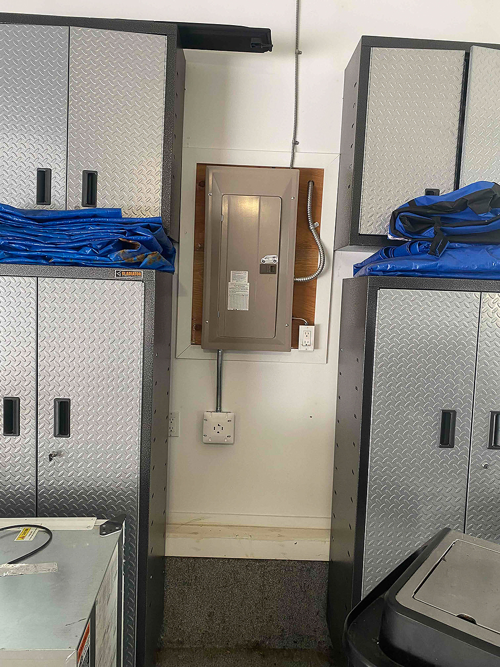 A licensed electrician's hands pointing to an outdated electrical panel, explaining the need for a service upgrade to the homeowner.