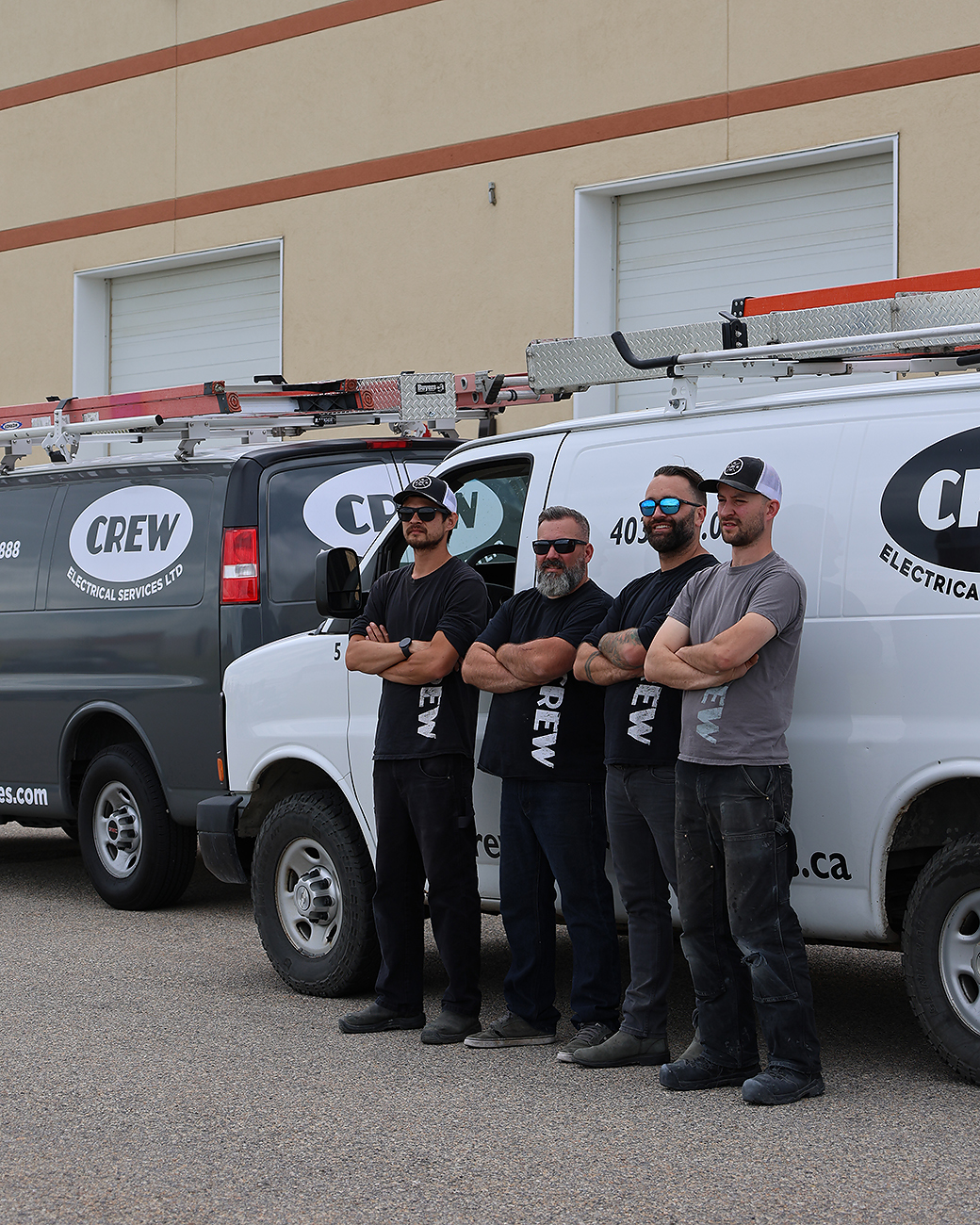 The professional CREW electrician team posing in front of their company vans. 