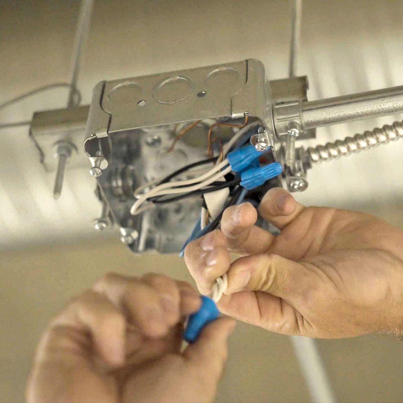 Crew Electrical Services electrician mounting a ceiling fan in a Calgary bedroom